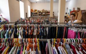 Люди розкладають одяг на столах у волонтерському центрі — допомога та передача речей у секонд-хенд чи для благодійності