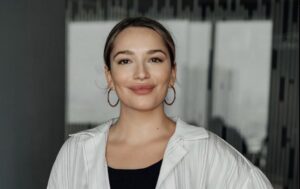 Зоя Мозгова та її кохана на фоні квітучого саду, усміхнені, в сонцезахисних окулярах — момент радості та відкритості