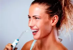 ригатор-прилад з резервуаром і насадкою, який очищає простір між зубами струменем води; зображення пристрою на білому фоні.